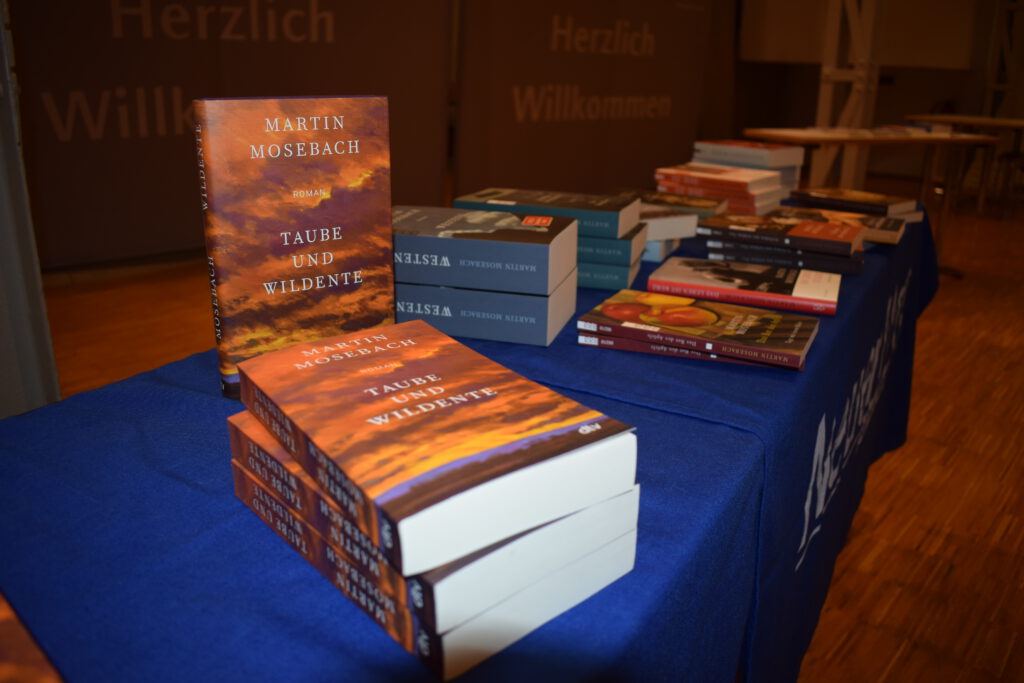 Bücherstapel von Martin Mosebachs Büchern auf einem Tisch mit blauer Tischdecke. 